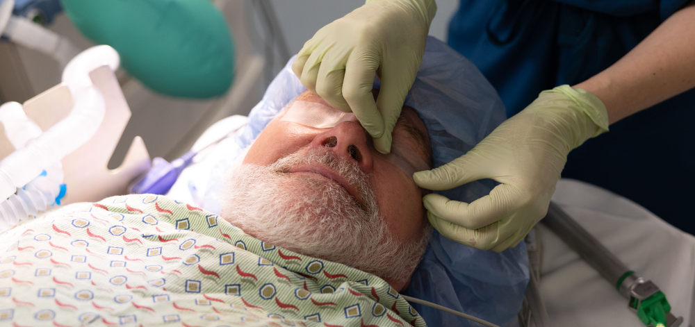 CRNA prepping an older adult for anesthesia by placing tape on eyes