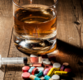 Alcohol, syringe, and pills sitting on a table.