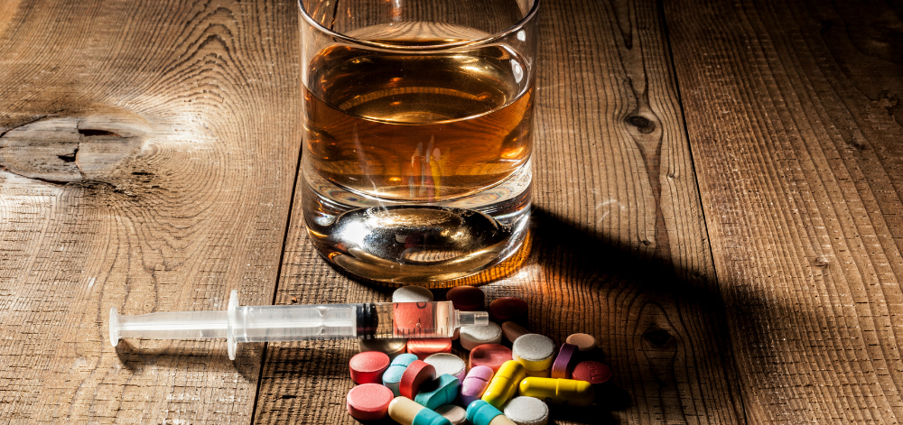 Alcohol, syringe, and pills sitting on a table.
