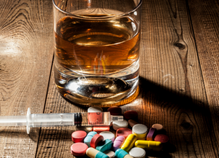 Alcohol, syringe, and pills sitting on a table.