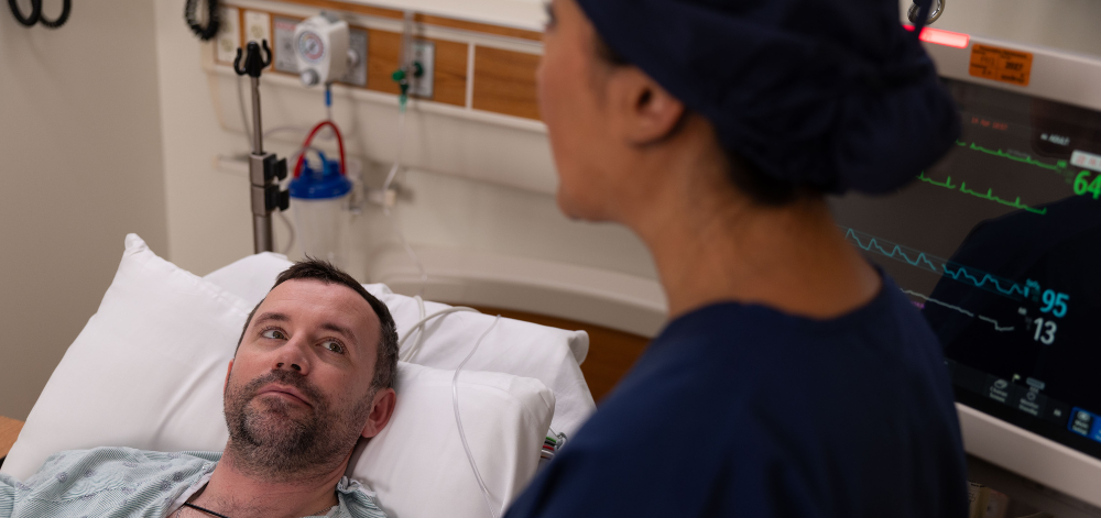 CRNA explaining procedure to a patient in bed