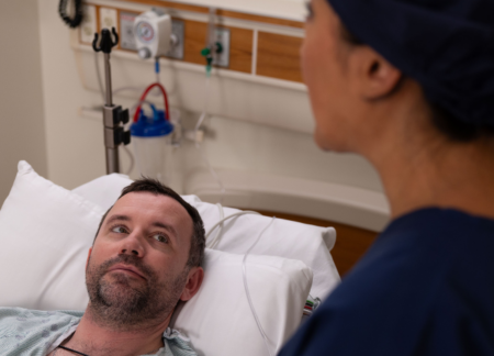 CRNA explaining procedure to a patient in bed