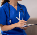 CRNA talking to a patient and writing on a chart