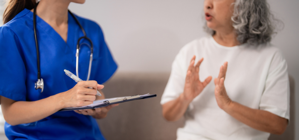CRNA talking to a patient and writing on a chart