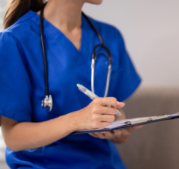 CRNA talking to a patient and writing on a chart
