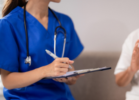 CRNA talking to a patient and writing on a chart