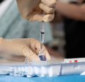Hands filling syringe from vial