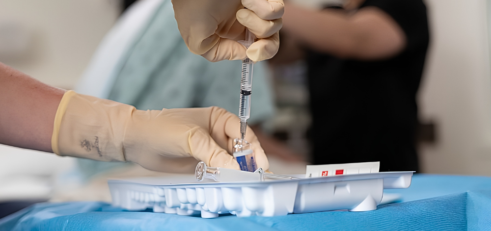 Hands filling syringe from vial