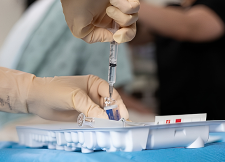 Hands filling syringe from vial