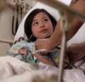 A young child in bed looks up at a CRNA