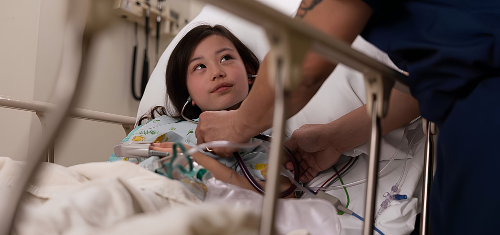 A young child in bed looks up at a CRNA